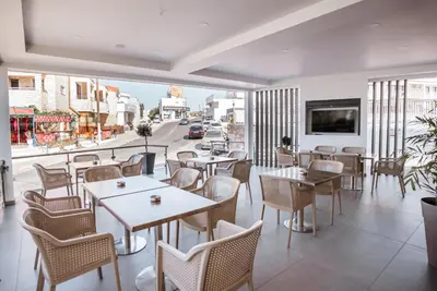 a restaurant with tables and chairs and a view of a street at Paul Marie Hotel Apartments in Ayia Napa