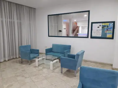 a waiting room with blue chairs and a mirror at Boronia Hotel Apartments in Larnaka