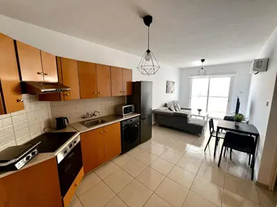 a kitchen with wooden cabinets and a table and a couch at Mackenzie 11 in Larnaka