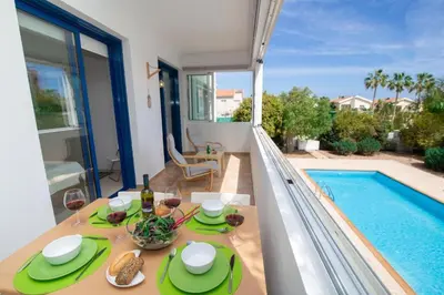a table with plates of food and wine and a pool at The Good Times Apartment in Protaras