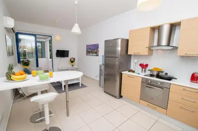 a kitchen with stainless steel appliances and a white table at The Good Times Apartment in Protaras