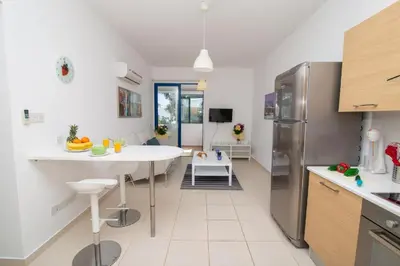 a kitchen with a table and a refrigerator at The Good Times Apartment in Protaras