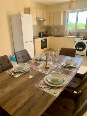 a kitchen with a wooden table with plates and wine glasses at Nissi 3 E8 Pool View Apt in Ayia Napa