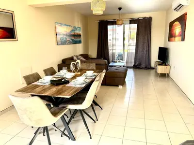 a living room with a wooden table and chairs at Nissi 3 E8 Pool View Apt in Ayia Napa