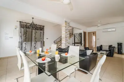 a dining room and living room with a glass table and chairs at Spacious Villa with Private Pool & Breathtaking Panoramic Ayia Napa views in Ayia Napa