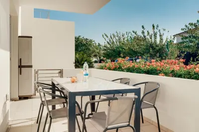 a table and chairs on a balcony with flowers at Cozy 2 Bedroom Family Apartment w/ Pool in Protaras