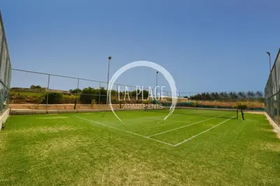 a tennis court with a net on a grass field at Cozy 2 Bedroom Family Apartment w/ Pool in Protaras