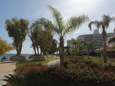 a park with palm trees and flowers in front of a building at GALATEX BEACH STUDIO in Limassol