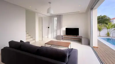 a living room with a black couch and a television at City Napa Seaview Villas - Villa 4 in Ayia Napa