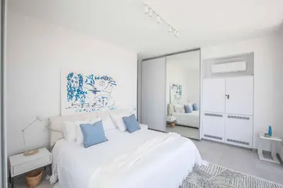 a white bedroom with a large white bed with blue pillows at Olivine Pearl OL3 in Protaras