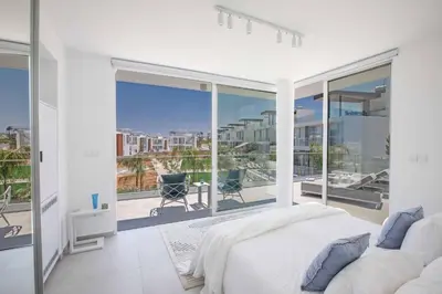 a white bedroom with a bed and a balcony at Olivine Pearl OL3 in Protaras