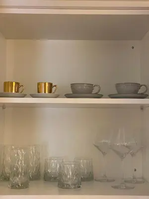 a row of glasses and bowls on a shelf at T&L Apartments Agiaos Tychonas in Limassol