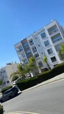 a large white building with cars parked in front of it at T&L Apartments Agiaos Tychonas in Limassol