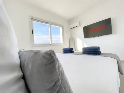 a white room with a bed and a window at Sunset Pearl Holiday Apt. - Ayia Napa in Ayia Napa