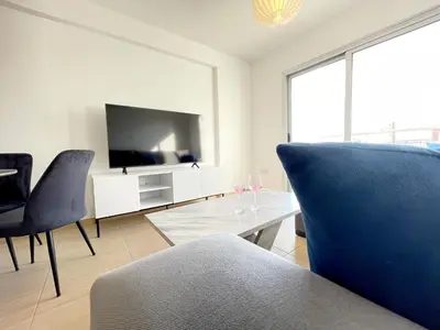 a living room with a flat screen tv and chairs at Sunset Pearl Holiday Apt. - Ayia Napa in Ayia Napa