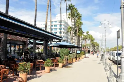 a sidewalk with tables and chairs and palm trees at 11 Suites - Sunrise Horizon Suite in Larnaka