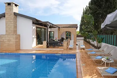 a swimming pool with chairs and a house at Villa Anthia - 2bed with Large Pool in Ayia Napa