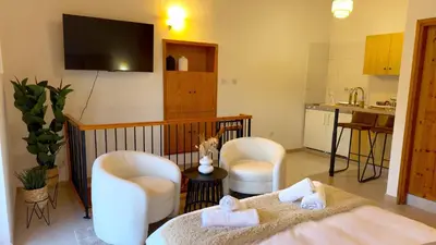 a living room with two white chairs and a kitchen at Maison Damianou Elegant Loft in Omodos