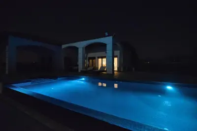 a swimming pool lit up at night at Villa Olivo Maroni in Maroni