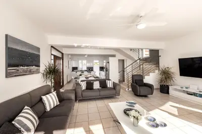 a living room with a couch and a tv at Faros Seaside Villa Larnaca in Pervolia