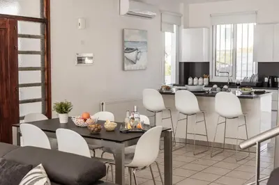 a kitchen and living room with a table and chairs at Faros Seaside Villa Larnaca in Pervolia