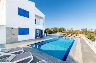 a swimming pool with lounge chairs and a house at Villa Malamar in Protaras