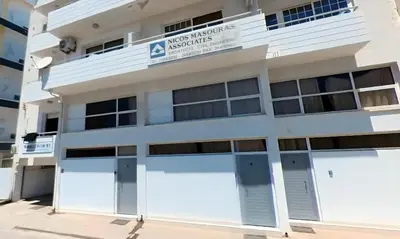 a white building with two garage doors at Duplex Apartment in Larnaka