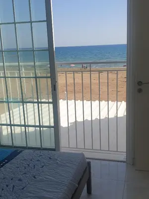 a bedroom with a view of the beach from a balcony at Sea Heart Villa Beachfront in Pyla