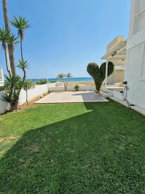 a yard with green grass and the ocean in the background at Sea Heart Villa Beachfront in Pyla