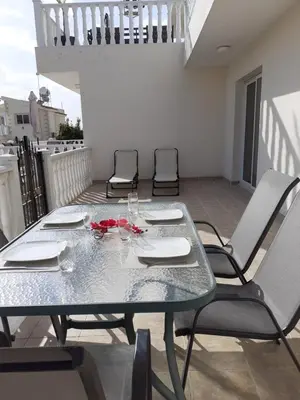 a glass table and chairs on a balcony with a table and chairs at Luxury Cozy Apartment near NISSI BEACH in Ayia Napa