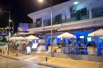 a restaurant with tables and umbrellas in front of a building at Eligonia Hotel Apartments in Ayia Napa