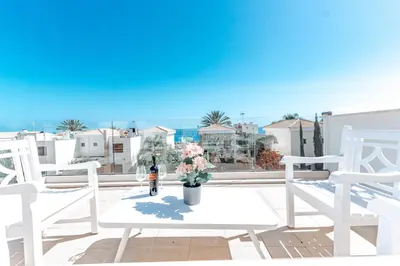 a white table with a vase of flowers on a balcony at WealthyStays Sunset Villa, 3min walk to Sea in Paralimni