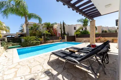 a villa with a swimming pool and two lounge chairs at WealthyStays Sunset Villa, 3min walk to Sea in Paralimni