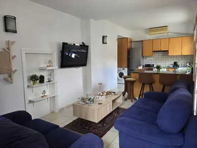 a living room with blue couches and a kitchen at Maryland Lodge kakopetria in Kakopetria