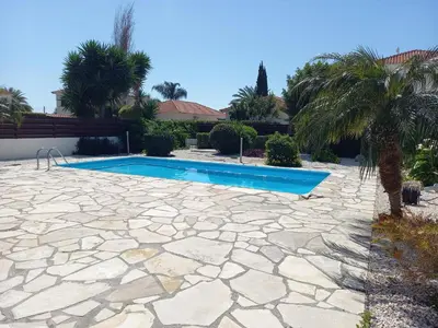 a swimming pool in a yard with a stone patio at Villa Penny in Pissouri