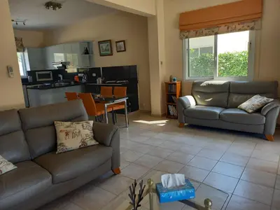 a living room with two couches and a kitchen at Villa Penny in Pissouri