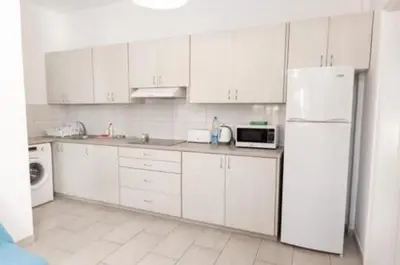 a kitchen with white cabinets and a white refrigerator at Miranda Beach House in Voroklini