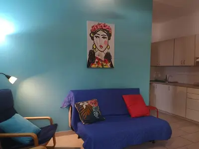 a living room with a blue couch and a painting on the wall at Miranda Beach House in Voroklini