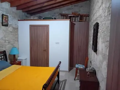 a bedroom with a yellow bed and a stone wall at TRADITIONAL HOUSE ARSOS in Arsos