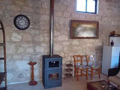 a living room with a stove and some chairs at TRADITIONAL HOUSE ARSOS in Arsos