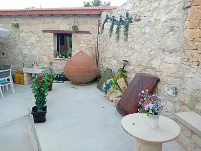 a patio with flowers and tables and a stone wall at TRADITIONAL HOUSE ARSOS in Arsos