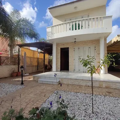 a white house with a balcony and a courtyard at Quiet holiday house near the beach in Meneou
