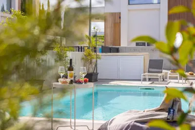 a swimming pool with wine glasses and a table next to it at Protaras By the Bay Villa 32 in Protaras