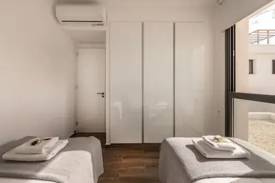 two beds in a white room with towels on them at Protaras By the Bay Villa 32 in Protaras
