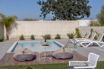a pool with two chairs and a table and a tablektop at Protaras By the Bay Villa 33 in Protaras