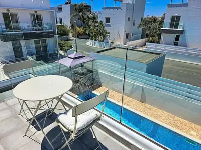 a balcony with a table and chairs and a pool at Nissi beach villa Holiday in Ayia Napa