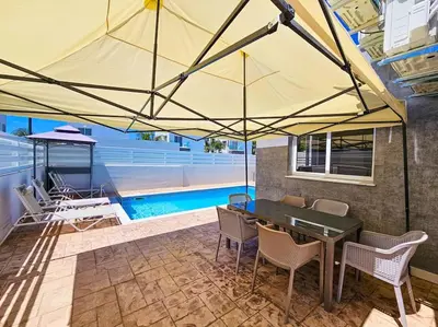 a patio with a table and chairs and a pool at Nissi beach villa Holiday in Ayia Napa