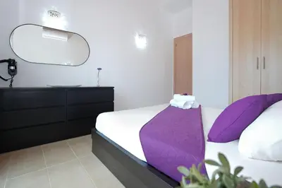 a bedroom with a bed with purple pillows and a mirror at Villa Lara - 3bed Bangalow with Large Pool in Ayia Napa