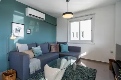 a blue living room with a couch and a window at Jayde 2-Bedroom Apartment in Larnaca in Larnaka