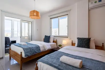 two beds in a room with windows at Jayde 2-Bedroom Apartment in Larnaca in Larnaka